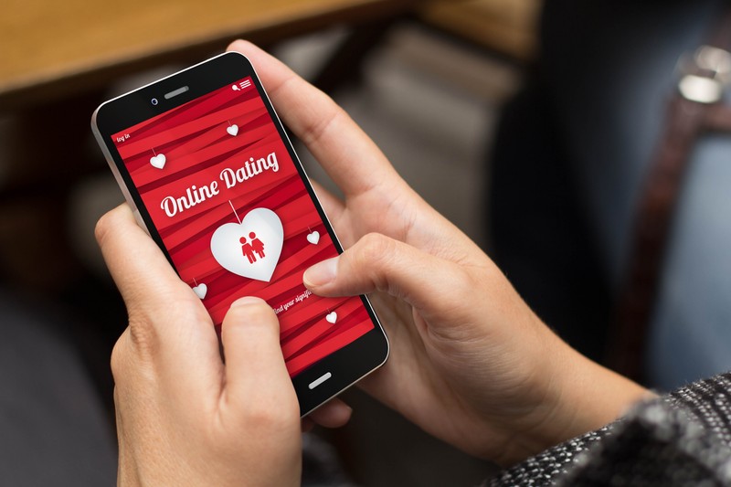 online love concept: girl using a digital generated phone with dating site on the screen. All screen graphics are made up.