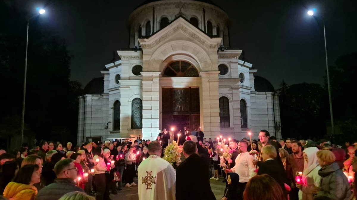 Credincioșii români la slujba de Paște din Noaptea de Înviere, stau în fața bisericii și iau lumină de la preot