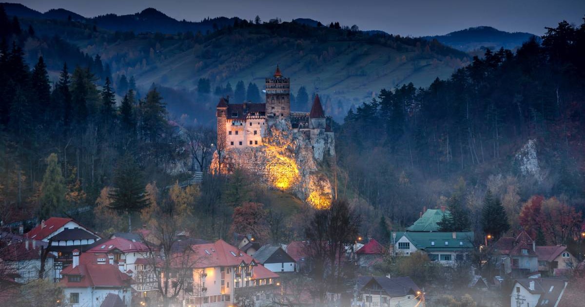 Castelul Bran, din Transilvania, România, cunoscut în lume drept „Castelul lui Dracula”, vazut pe inserat, cu lumini aprinse si case in ceata la baza lui, rămâne simbolul misterului din Transilvania și una dintre cele mai vizitate destinații de Halloween din Europa