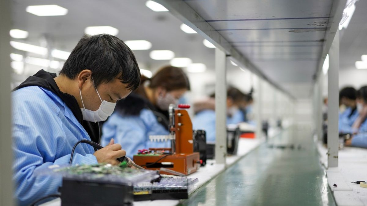 Angajații lucrează în atelierul unei companii de electronice din Chongqing, China