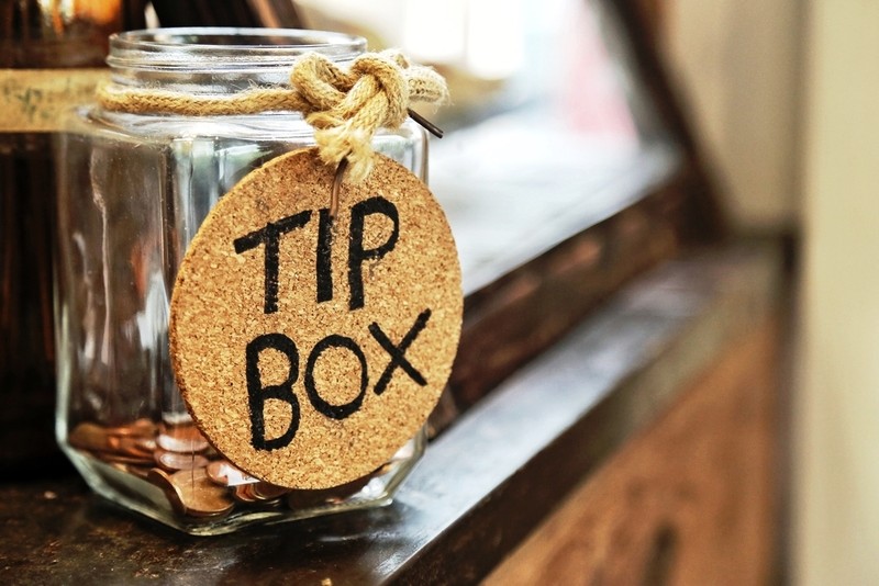 Vintage retro glass jar with hemp rope tie tip box tag and few coins inside on wood counter