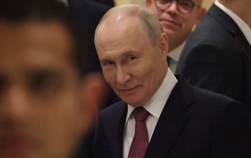 Vladimir Putin, în timpul unui eveniment oficial. Este înconjurat de oameni și poartă un costum albastru