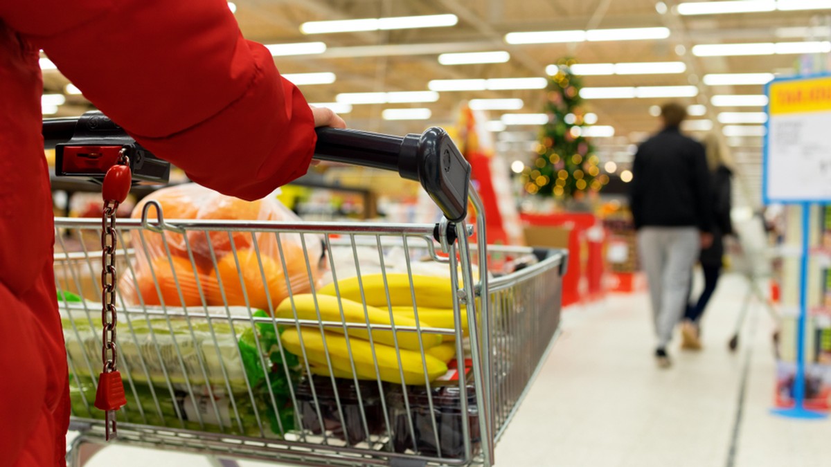 Program magazine de Crăciun 2022 - Imagine cu o femeie cu un cărucior în care îşi pune cumpărăturile de Crăciun, într-un supermarket