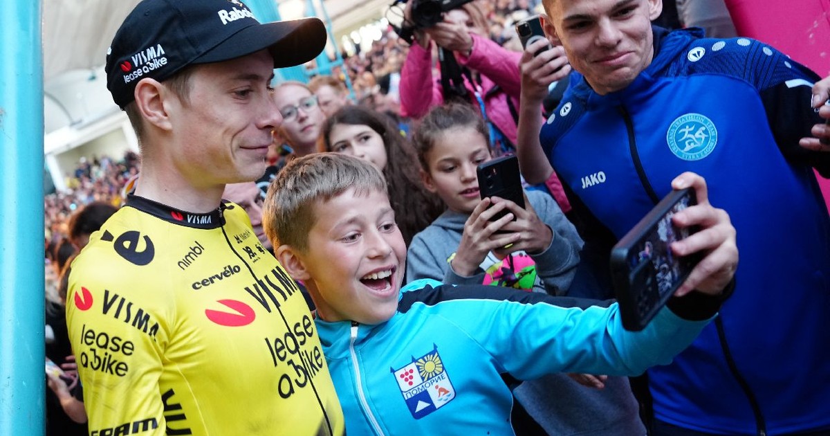 Ciclistul Jonas Vingegaard îmbrăcat într-un echipament galben face un selfie cu de un băiețel bulgar, îmbrăcat în echipament albastru. Sunt înconjurați de mulți oameni.