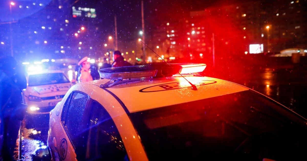 Două mașini de Poliție, cu girofarele pornite, noaptea, pe o stradă din București
