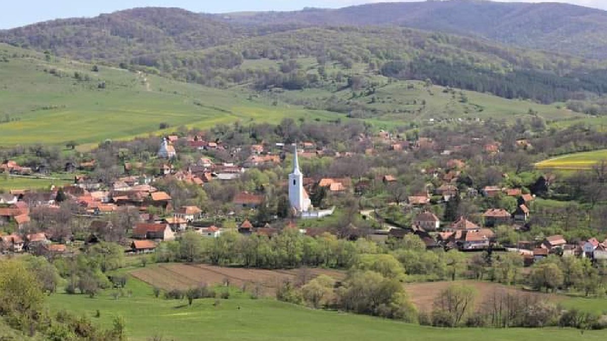 Imagine cu satul Crăciunel din Transilvania, ăn timpul verii. În imagine se distinge turnul alb al unei biserici