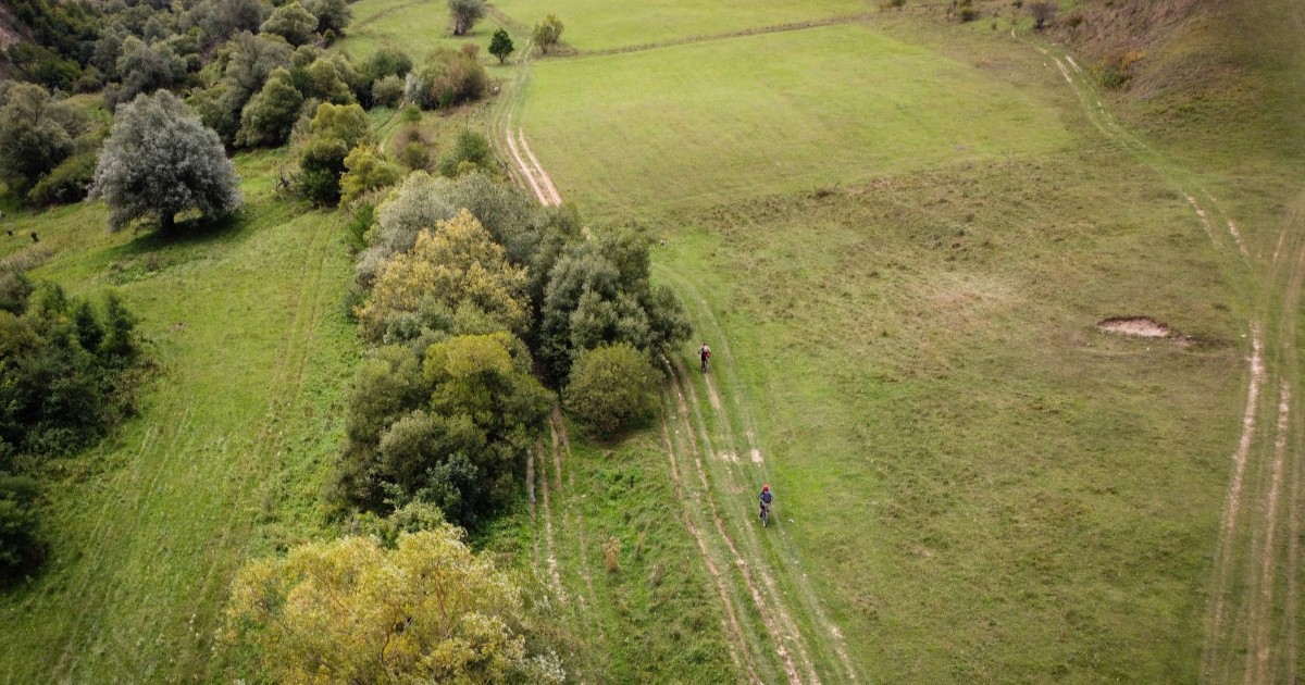 O vedere aeriană care surprinde doi oameni pe bicicletă, pe Via Transilvanica.