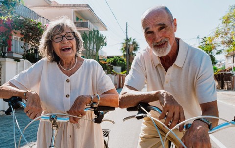 Cuplu senior fericit plimbându-se cu bicicleta în aer liber, zâmbind