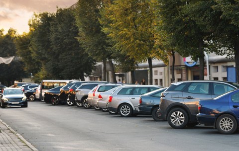 Rânduri de mașini parcate strâns de-a lungul drumului pe o stradă rezidențială îngustă