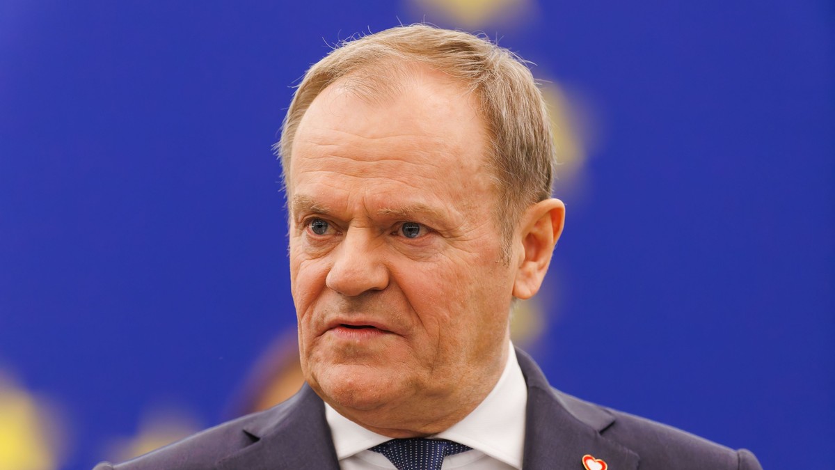 Premierul Poloniei, Donald Tusk, îmbrăcat în costum și cu steagul UE în spate