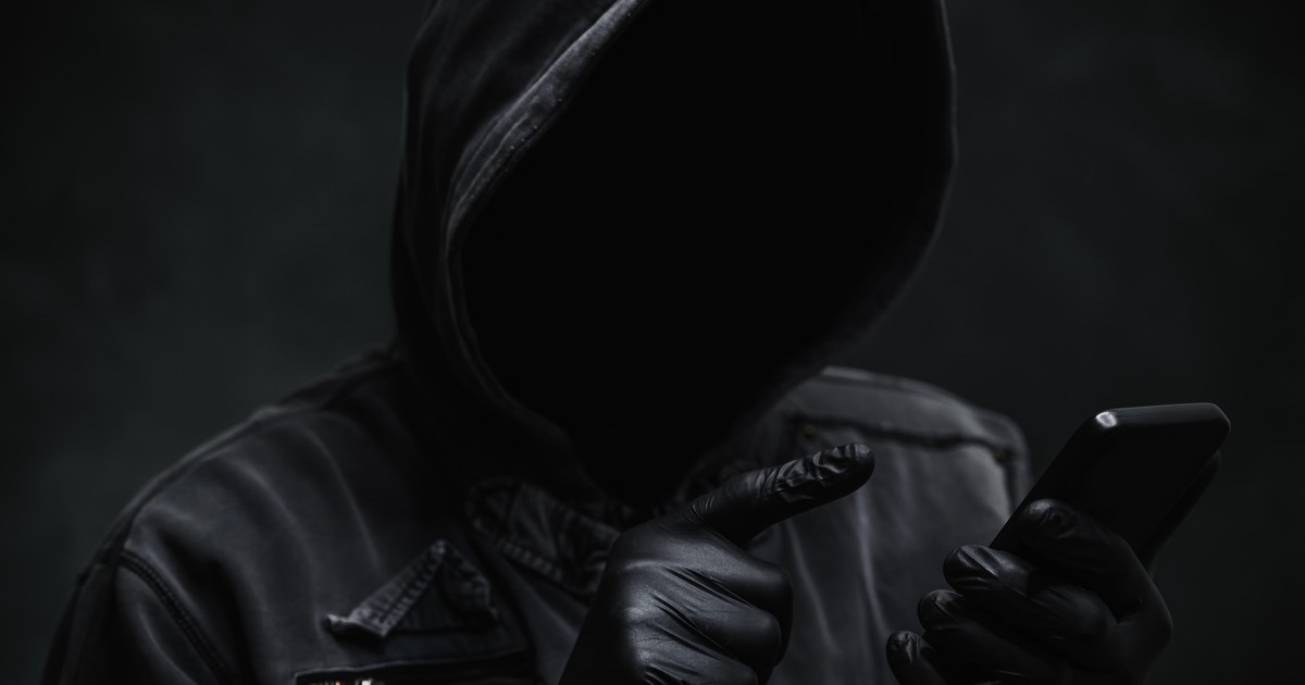 Hacker surprins cu mânuși în mâini ținând un telefon