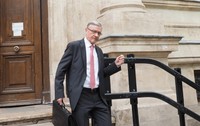 Un barbat in costum negru si camasa alba cu cravata roz iese din tribunal