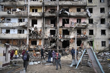 Oamenii se adună în fața unui bloc dintr-o suburbie a Kievului, lovit de obuze militare ruse, 25 februarie 2022. Foto: Profimedia
