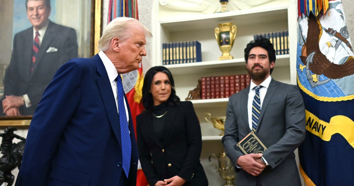 Tulsi Gabbard (centru) și soțul ei, Abraham Williams (dreapta), privesc cum președintele american Donald Trump pleacă după ce a răspuns la întrebările presei în timpul unei ceremonii de învestire a lui Gabbard în funcția de director al serviciilor de informații naționale (DNI) în Biroul Oval al Casei Albe din Washington