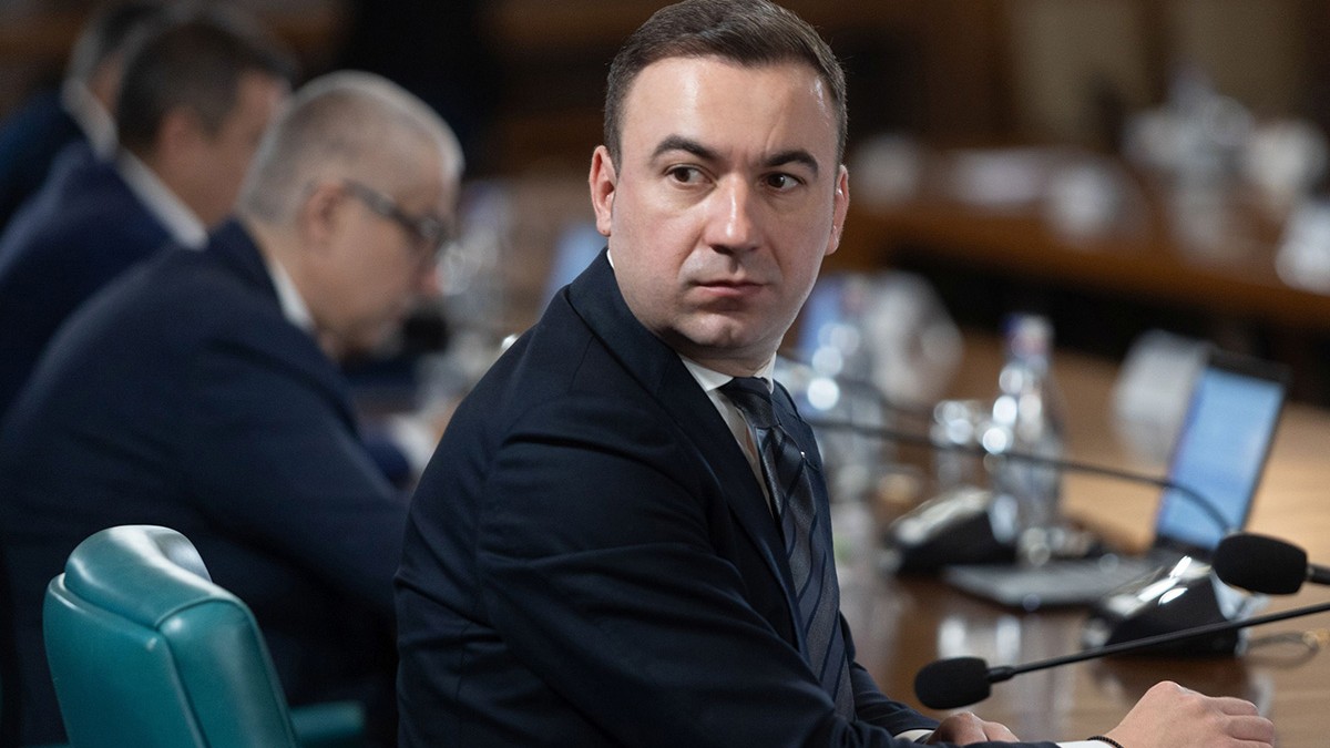 Bogdan Ivan, ministrul Investițiilor și Proiectelor Europene, participă la o ședință de guvern, este întors la masă și privește în spate