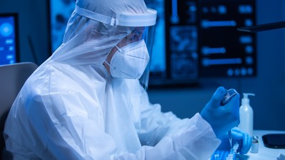 Doctor in protective suit is doing a science experiments and developing vaccine in a modern laboratory. Genetic engineers workplace. The concept of science and medicine.