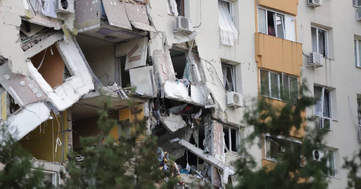 Pereții căzuți ai celor două etaje unde a avut loc explozia din Rahova, bucățile de beton din fațada blocului atârnă în jos. Geamurile de la ferestre sunt sparte și perdelele atârnă de marginea blocului