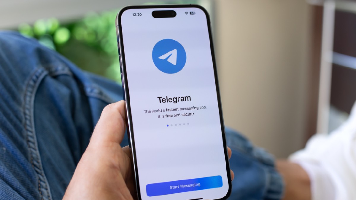 Mână de bărbat ținând un iPhone 15 Pro Max de la Apple cu serviciul de rețea socială Telegram pe ecran.