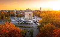 Fotografie aeriană care înfățișează Arcul de Triumf, un monument istoric din București, în timpul unui frumos apus de toamnă. 