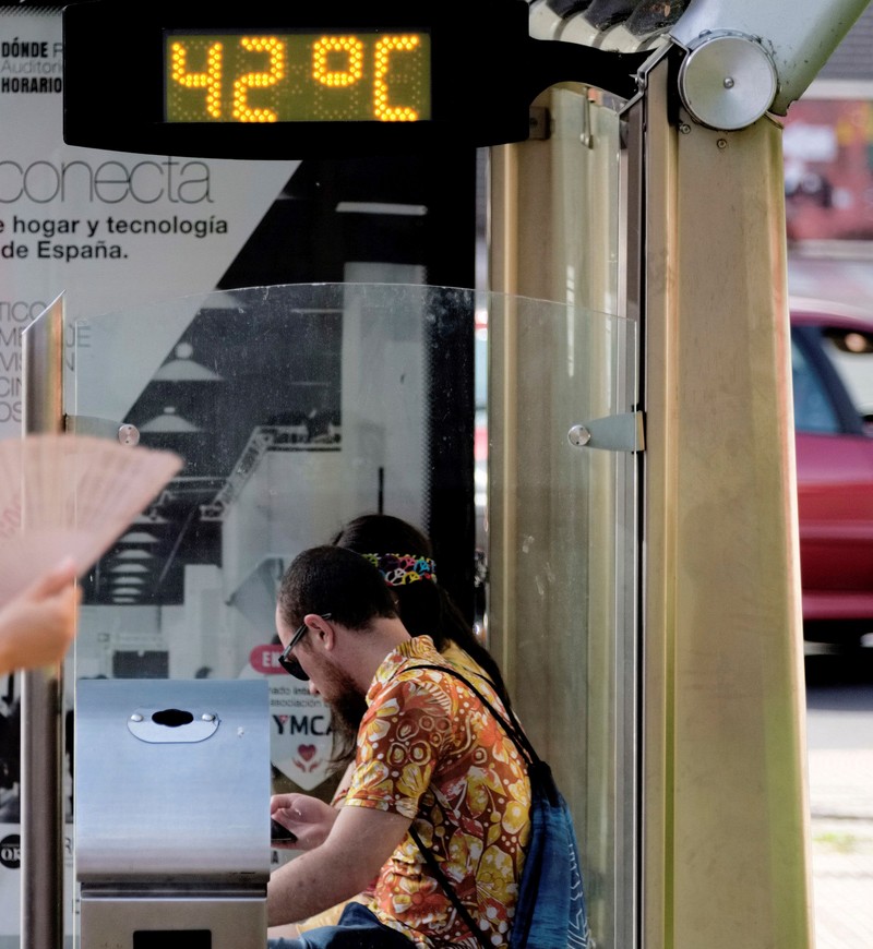 epa07682238 A women uses a fan to keep cool as a thermometer reads 42 degrees Celsius at a bus stop in Logrono, La Rioja, Spain, 29 June 2019. Spain is suffering a heat wave that is rising temperatures over 40 degrees Celsius. EPA-EFE/ABEL ALONSO