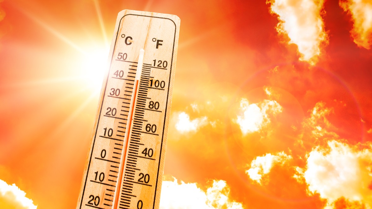 În imagine este prezentat un termometru clasic din lemn care indică o temperatură ridicată de aproape 40 de grade Celsius, fiind plasat pe fundalul unui cer incandescent în nuanțe aprinse de portocaliu și roșu, cu un soare puternic și strălucitor.