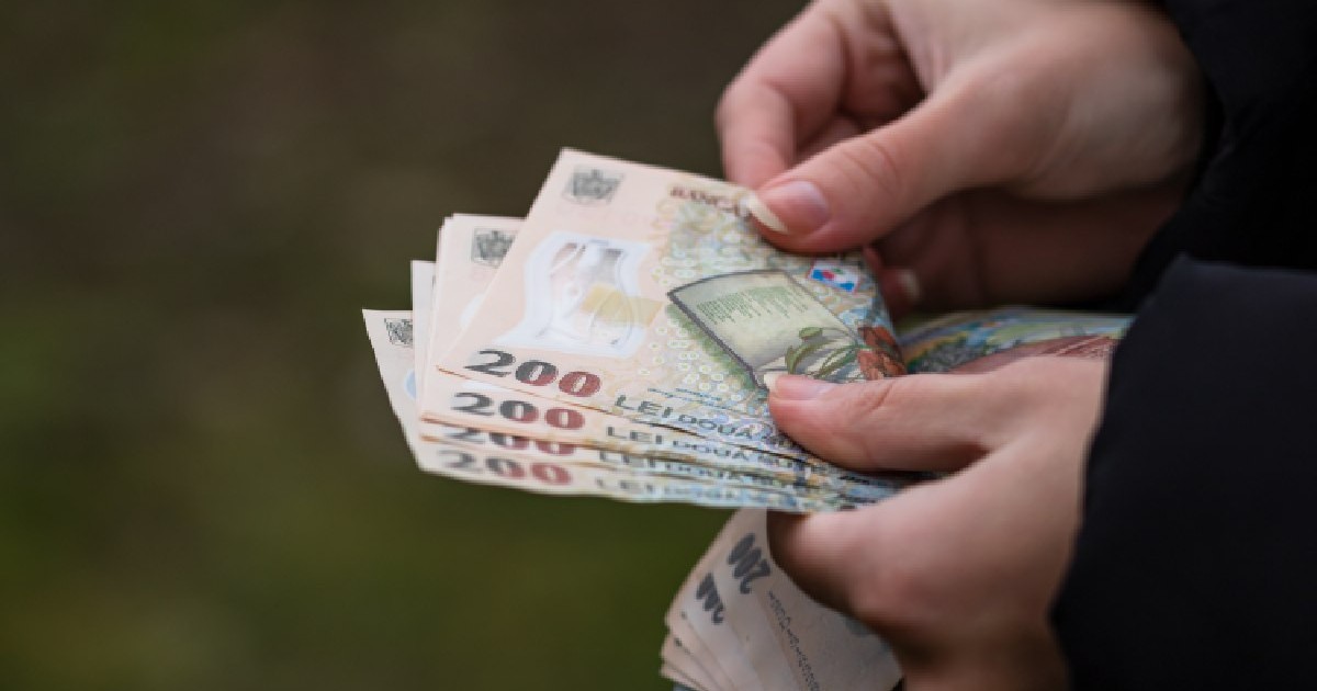 Un prim-plan cu mâinile unui om care numără bani