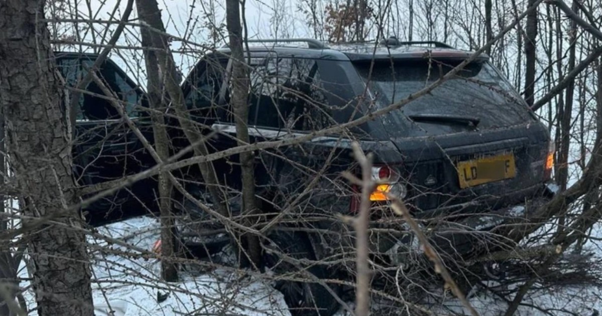 Un Range Rover negru cu numere străine, abandonat pe marginea drumului, între crengile unui copac, căzute pe zăpadă