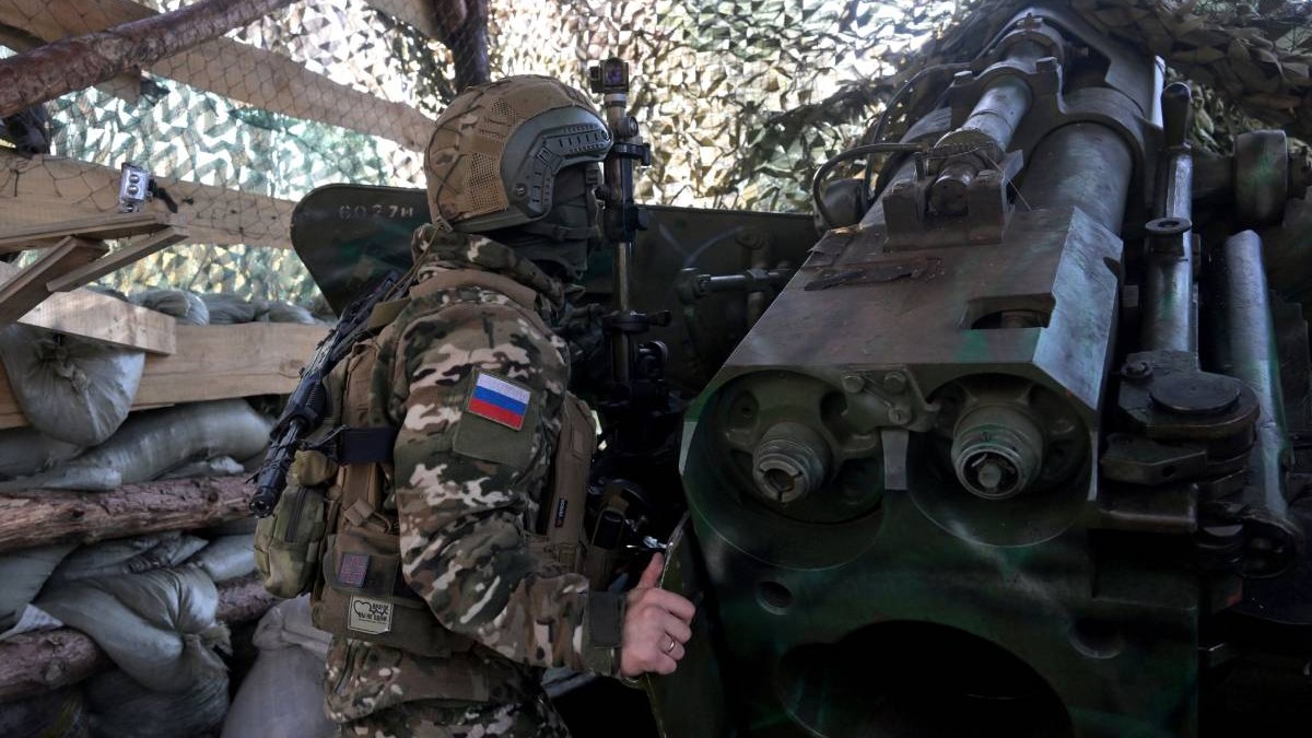Un soldat rus pe front, stând camuflat lângă un lansator de rachete.