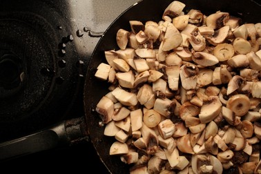 pieces of mushrooms in a pan. pieces of raw mushrooms in a pan. cooking raw mushrooms