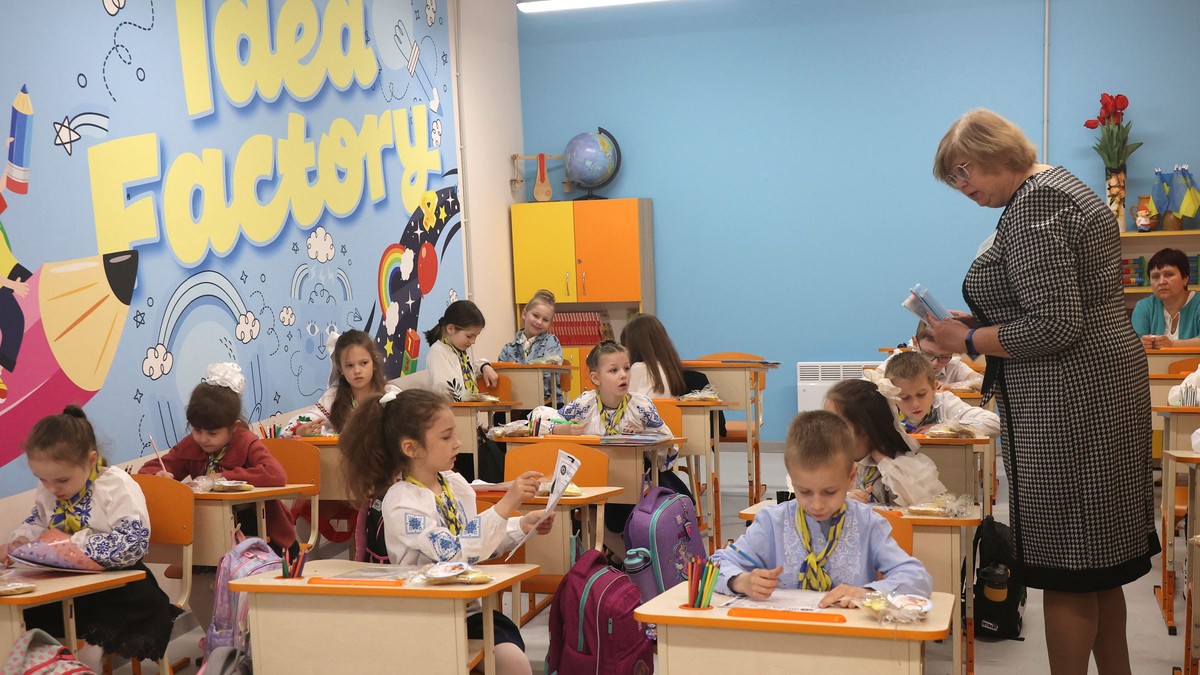 Elevi de clasa întâi care stau în bănci și învățătoarea lor