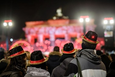 epa07255532 Visitors with straw hats in the German national colors attend the show program in front of the Brandenburg Gate during the beginning of the New Year's Eve celebrations in Berlin, Germany, 31 December 2018. EPA-EFE/CLEMENS BILAN