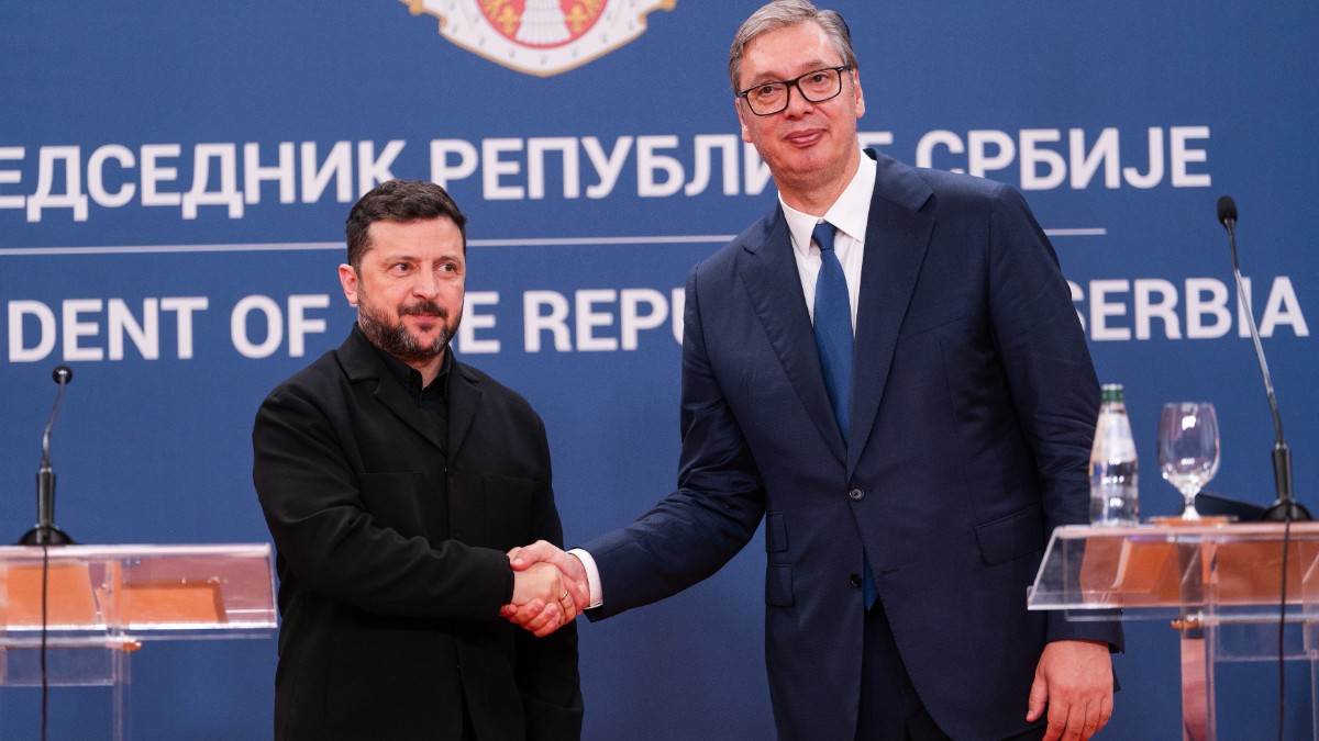 În imagine, Volodimir Zelenski și Aleksandar Vučić apar împreună la o conferință de presă, în fața steagului și a însemnelor prezidențiale ale Serbiei. Cei doi lideri își strâng mâna, zâmbind, în timpul întâlnirii oficiale de la Belgrad.