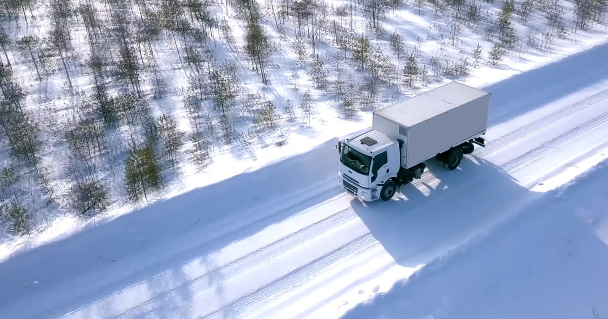 Camion surprins în timp ce circulă pe un drum acoperit de zăpadă.