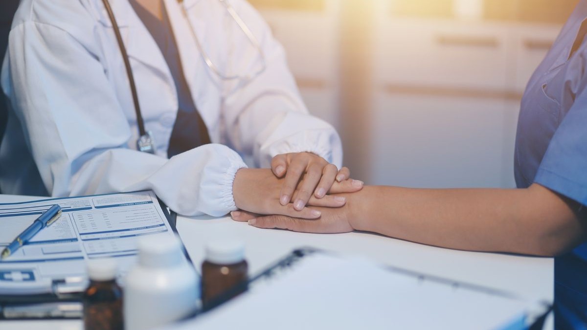 Vedere de aproape a unei medic generalist care mângâie palmele unei paciente.