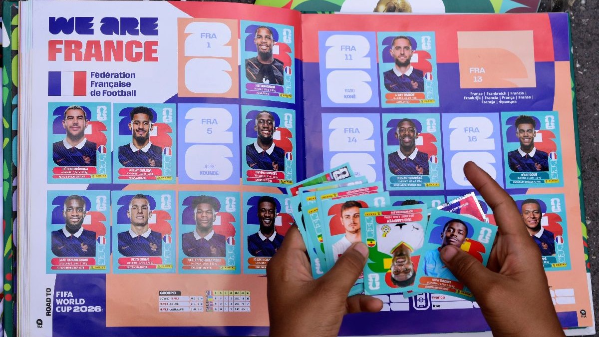 Două mâni țin cartonașe panini deasupra unui album, la paginile echipei Franței