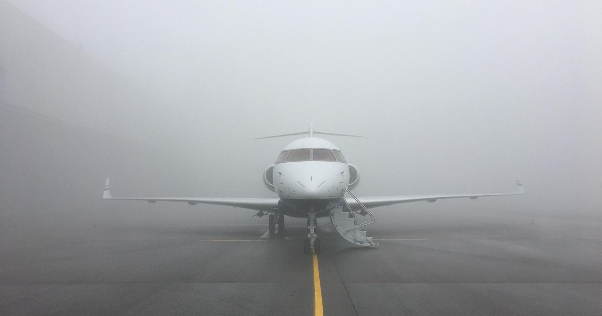avion pe pista de decolare, înconjurat de ceață densă