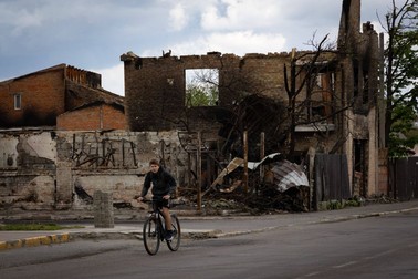 Un copil pedalează pe străzile din Bucha, pe lângă clădirile distruse | FOTO: Profimedia