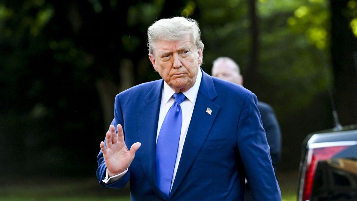 Donald Trump, îmbrăcat în costum albastru și cu o insingnă cu steagul SUA la rever, face cu mâna în timp ce sosește la summitul NATO de la Haga, Țările de Jos, 25 iunie 2025