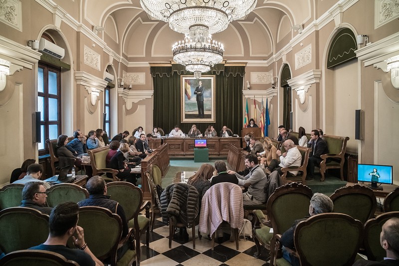 Sala de ședințe, Primăria din Castellón de la Plana. În mijloc, primarul orașului, Amparo Marco. În picioare, la pupitru (atril) vorbește românca Monica Barabas de la partidul socialist spaniol PSOE. Primul de pe rândul de sus, dreapta, este Manuel Păduraru de la partidul Ciudadanos. Ambii români sunt consilieri la Primăria din Castellón de la Plana.