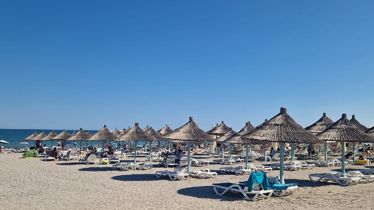 Umbrelute de paie si sezlonguri pe plaja la mare. Litoralul romanesc.