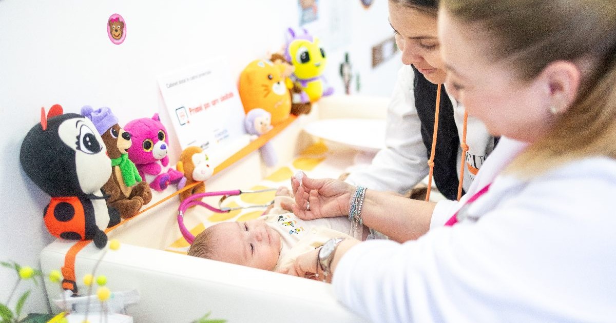 Un bebelus intr-o cutie patut, consultat de medic, cu mama langa el.Pacientul din rural nu are acces suficient la servicii De ce lasă medicii de familie satele din România