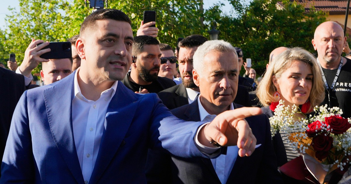 Geoge Simion arată cu mâna stângă spre cineva. Lângă el se află Călin Georgescu și alte persoane.