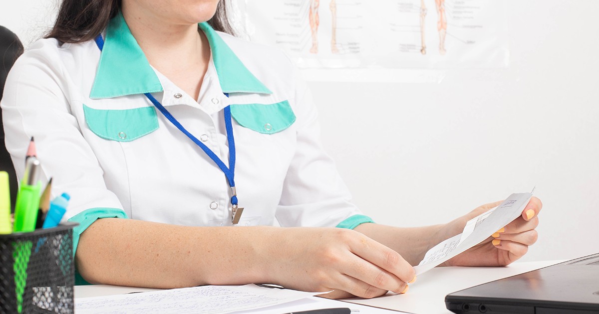 O doctoriță ține în mână un certificat de concediu medical în cabinetul unui centru medical. Conceptul de acordare a concediului medical de către medic