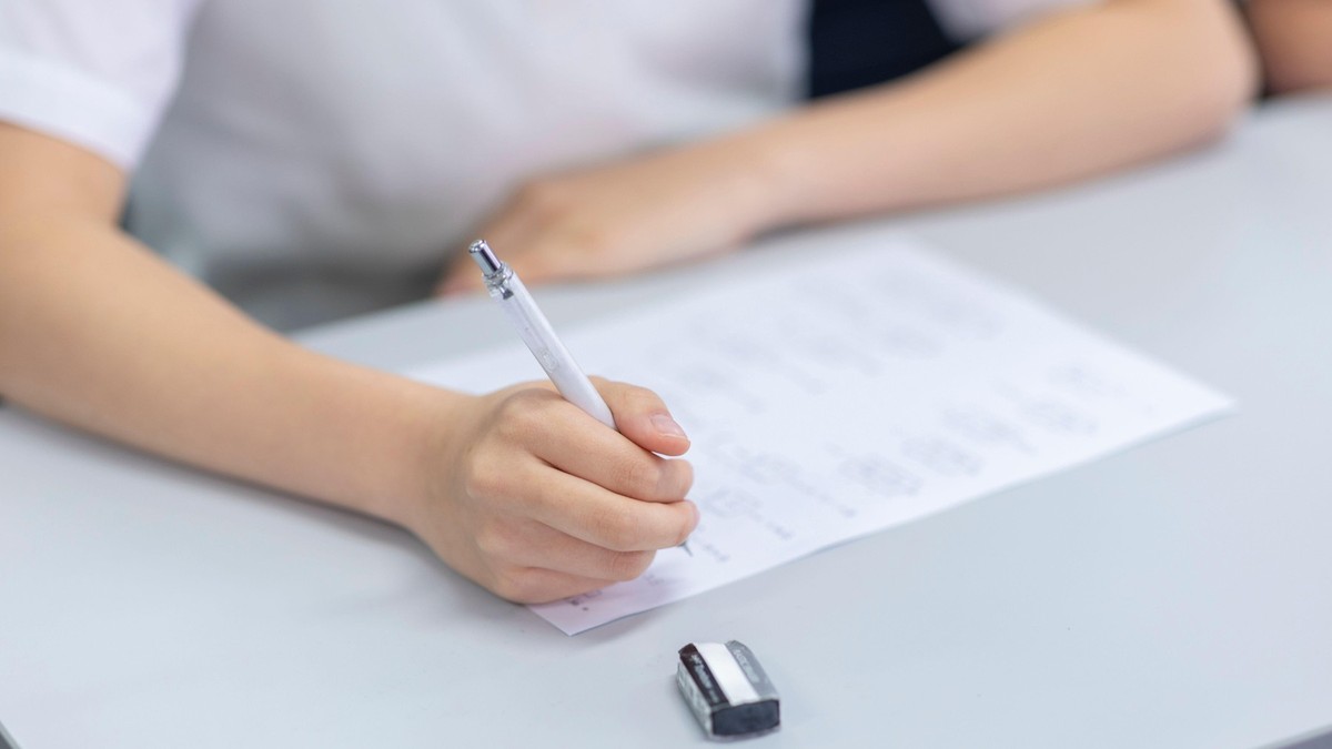 Imagine cu un elev în bancă în timpul unui examen. Ține un pix în mână