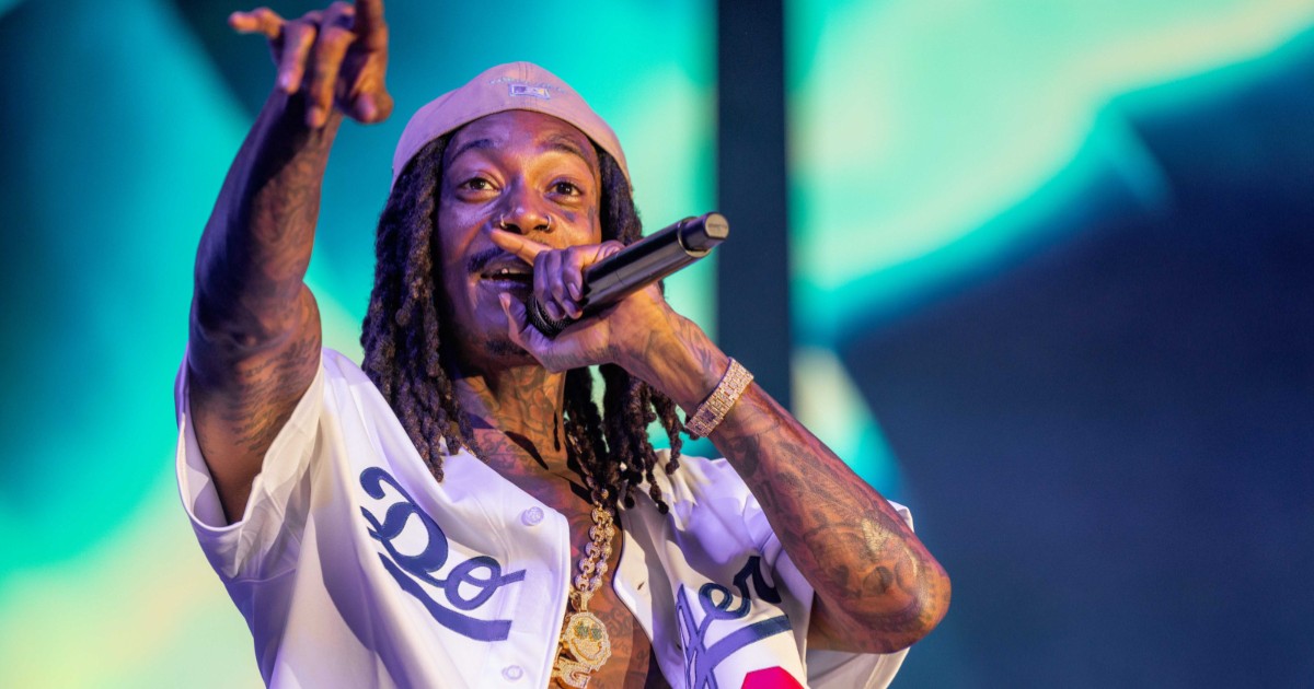 Wiz Khalifa pe scenă, cântând la microfon, în timpul unui concert