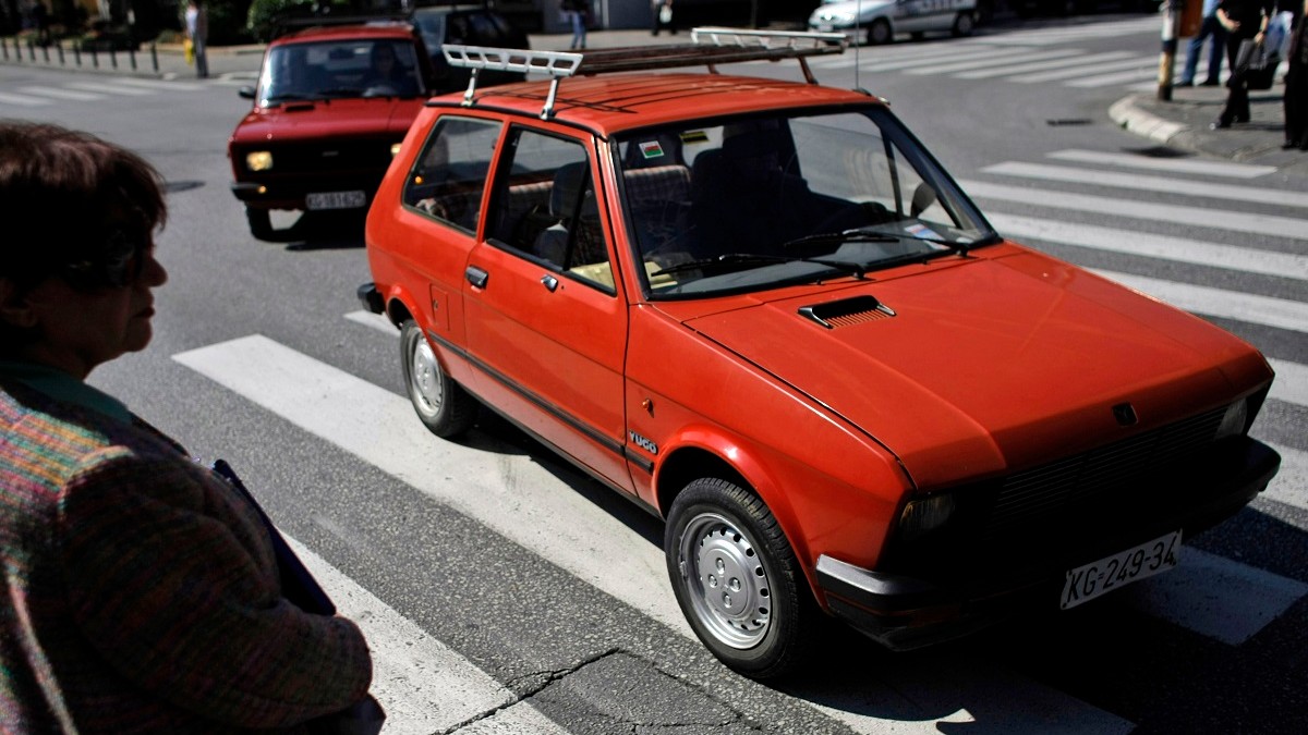 O mașină roșie Yugo merge pe o trecere de pietoni de pe o stradă din Belgrad