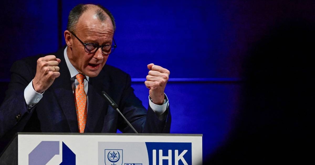 Cancelarul german Friedrich Merz, in costum negru camasa alba si cravata portocalie, cu pumnii stransi, ridicati, in timp ce vorbeste la microfon, la pupitru, la Camera de Comerț și Industrie din Halle, în estul Germaniei, pe 14 ianuarie 2026.