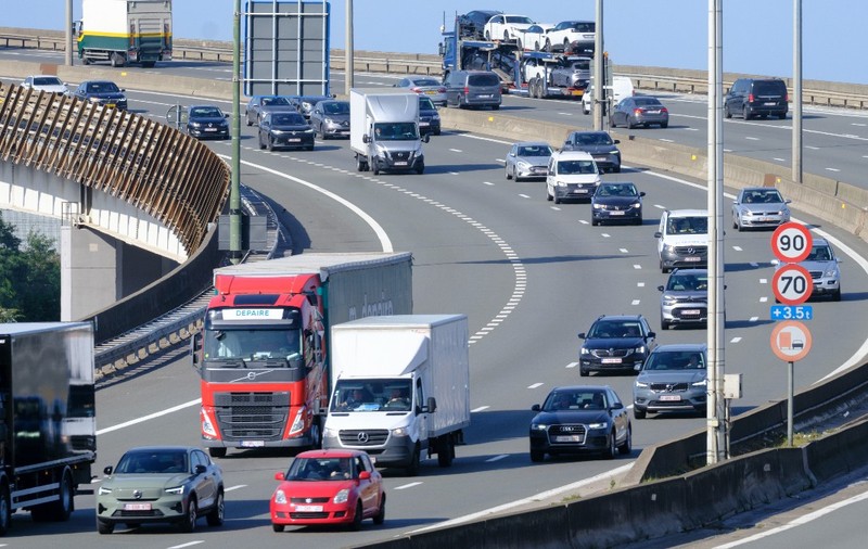 Trafic intens de autoturisme, camionete și camioane în deplasare pe un nod rutier supraetajat al unei autostrăzi.