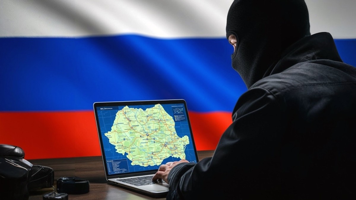un agent rus cu cagula se uita pe ecranul unul laptop pe care este harta romaniei, iar pe fundal steagul rusiei. Foto ilustrativ