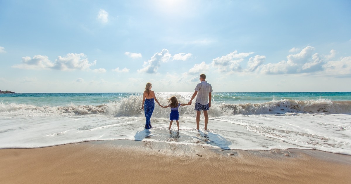 destinații ieftine în Europa, pentru o săptămână la plajă, în 2018. Doi părinții cu o fetiță, care intră în valurile mării